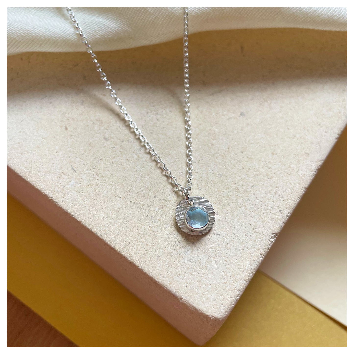 Sterling Silver and Blue Topaz Hammered Disc Pendant.