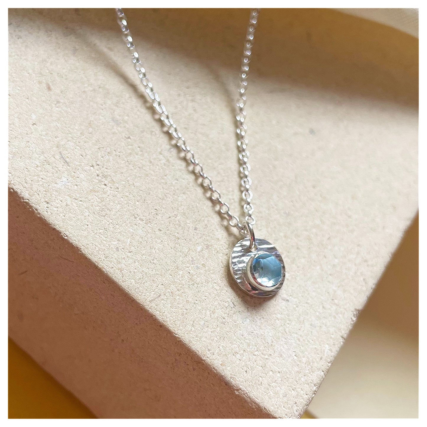 Sterling Silver and Blue Topaz Hammered Disc Pendant.