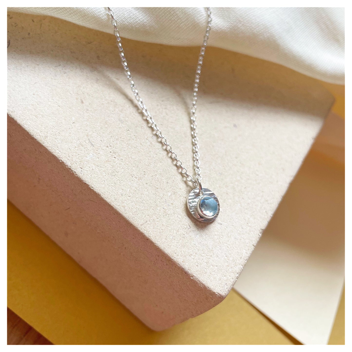 Sterling Silver and Blue Topaz Hammered Disc Pendant.