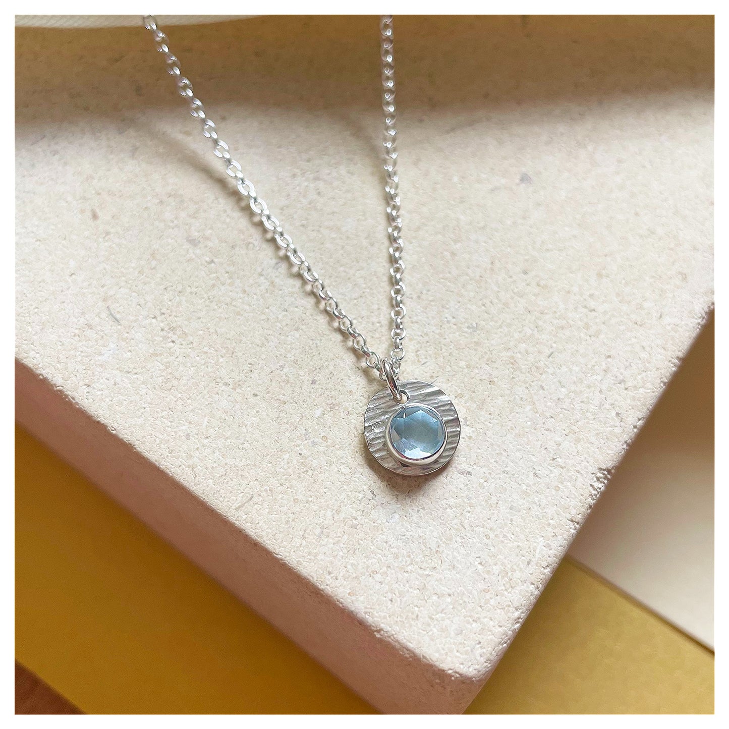 Sterling Silver and Blue Topaz Hammered Disc Pendant.